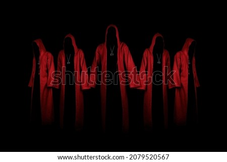 Group of mystery people in a red hooded cloaks.  Unrecognizable person. Hiding face in shadow. Ghostly figure. Satanic sect member. Conspiracy concept. Isolated on black. Royalty-Free Stock Photo #2079520567