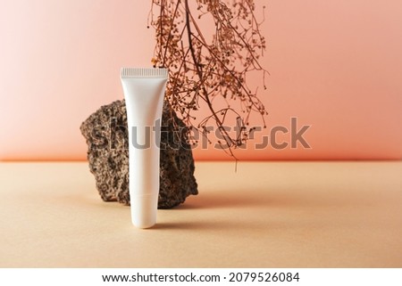 White plastic tube and stone and natural dry herb creative still life cosmetic photography. Lip balm blank empty mockup