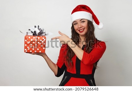 Beautiful woman with christmas gifts box on white background with copy space. Young woman in red santa claus hat holding present box. Happy Snow Maiden girl. Christmas and New Year holiday concept