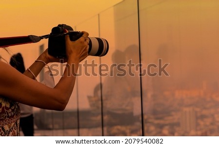 Close up of  woman tourist photographer using a camera takeing a picture of view in the city skyline  with sunset background