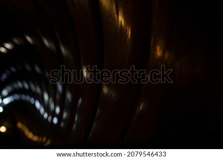 Reflection of dim light in a sparkling transparent surface. The game of reflections of electric light in the tunnel. Abstract photo of night lights in the city.