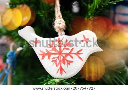 wooden bird handmade hanging from a decorated Christmas tree.Christmas tree decoration background.bird in Christmas celebrate winter season in holiday eve, Christmastime.freedom, peace, peaceful hope.