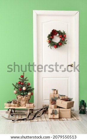 Christmas tree and presents with fir branches near door