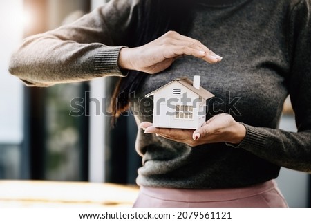 Real estate agent gesturing to protect homes, housing insurance concept.