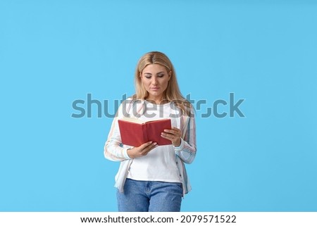 Beautiful woman with book on color background