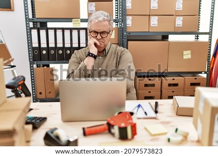 Senior caucasian man working at small business ecommerce with laptop thinking looking tired and bored with depression problems with crossed arms. 