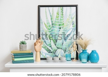 Shelf with wooden hand and picture near white wall in room