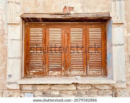 Old rustic weathered wooden window closed shutters on stone wall