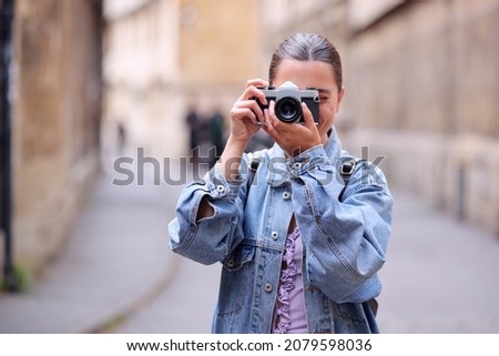 Young Woman In City Street Taking Photo Towards Camera On Retro Style Digital Camera