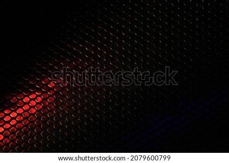 Abstract metallic hexagon background black with red. A red ray of light on the texture of the scales. Dark red wallpaper with scales pattern. Mesh design modern luxury futuristic technology background