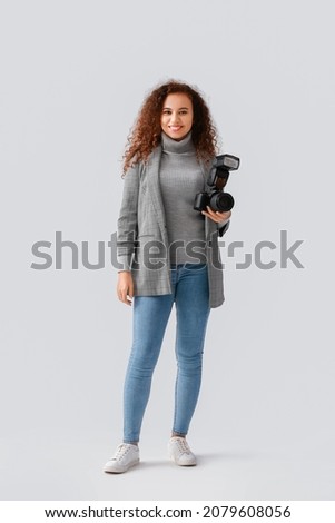 Female African-American photographer on light background