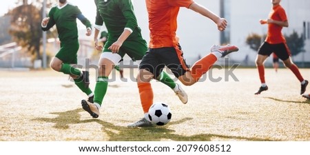 Adult Soccer Players Running After Ball and Kicking League Match. Group of Footballers in a Duel. Soccer Players in Orange and Green Jersey T-shirts Royalty-Free Stock Photo #2079608512