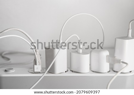 Many chargers plugged into maltiple electrical outlet on white background. Concept of electricity consumption. Royalty-Free Stock Photo #2079609397