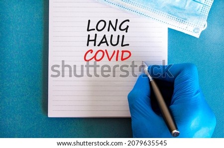 COVID-19 long-haul covid symptoms symbol. White card with words Long haul covid. Doctor hand, pen, beautiful blue background, copy space. Medical, COVID-19 long-haul covid symptoms concept.