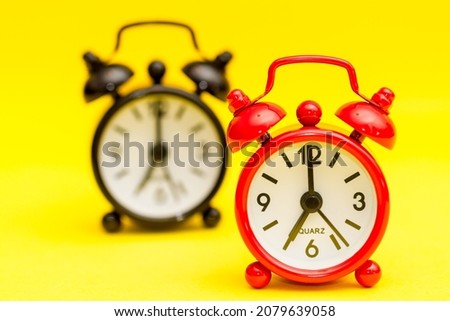 A pair of alarm clocks on yellow.