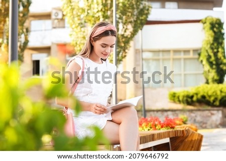 Beautiful woman reading blank book outdoors