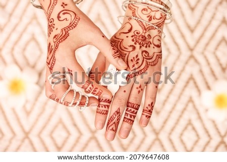 Beautiful female hands with henna tattoo and flower on light background