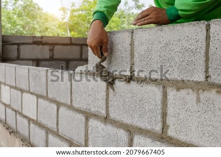 masonry worker make concrete wall by cement block and plaster at construction site Royalty-Free Stock Photo #2079667405