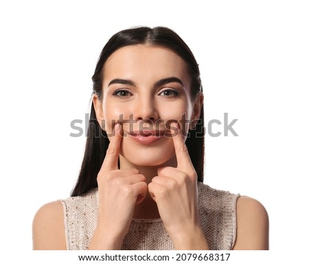 Young woman doing face building exercise against white background Royalty-Free Stock Photo #2079668317