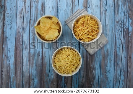 Variety of crunchy delicious potato chips for a tasty snack break on blue wooden background