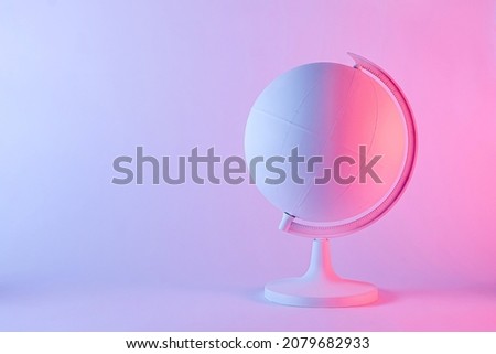Model of a globe with blank map in pink and purple gradient light. Geography concept with copy space