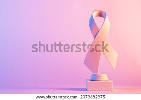 Studio close-up of the pink painted 3d symbol of the breast cancer awareness ribbon with shadow against pastel background for copy space