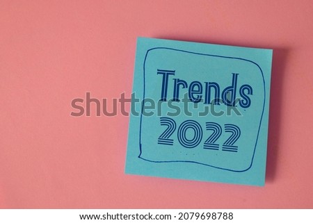 Note with the inscription Trends 2022 on pink background. Top view.