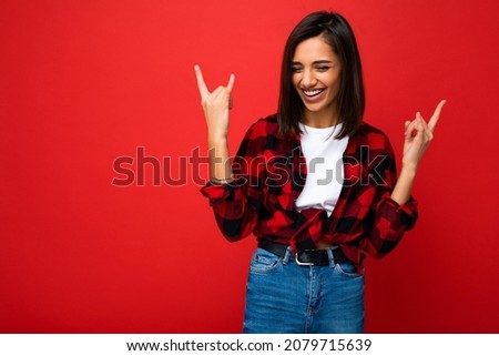 Photo of positive happy funny joyful smiling young fascinating beautiful attractive nice brunette woman with sincere emotions wearing casual white t-shirt and red shirt isolated over red background