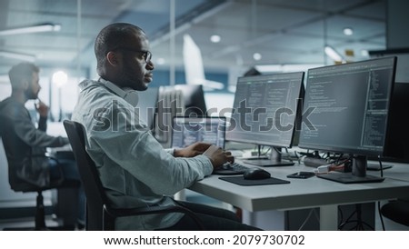 Authentic Office: Enthusiastic Black IT Programmer Starts Working on Desktop Computer. Male Website Developer, Software Engineer Developing App, Video Game. Terminal with Coding Programming Language Royalty-Free Stock Photo #2079730702