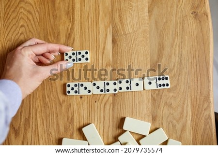 Top view of woman hand play white domino games on wooden table background with copy space, board game concept