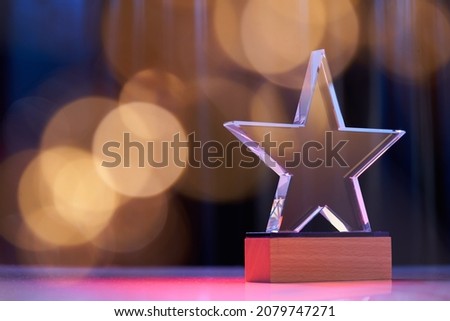 Star shape trophy with color light against stage curtain as background                             Royalty-Free Stock Photo #2079747271