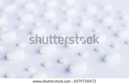 White pills on a white background. Oblong and round pills close-up. Healthcare and medicine.	

