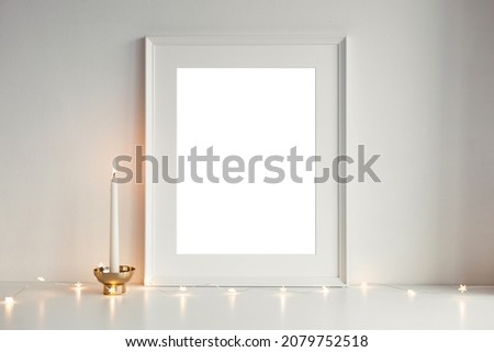 Layout frame with blank copy space for your advertising content, text or greeting, small star shaped garland lights and candle in golden cup against white background. Christmas decoration