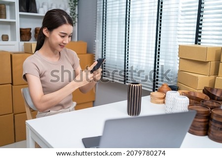 Asian business woman take photo of vase products for doing marketing. Attractive beautiful worker use laptop computer enjoy post advertising sell picture for online purchase goods shopping in website.