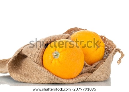 Two organic bright yellow oranges with jute bag, close-up, isolated on white.