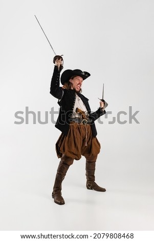 Knight of knife. Portrait of brutal man, pirate in vintage costume raising swords isolated over white background. Combination of medieval and modern styles. Concept of history. Copyspace for ad.