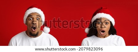 Closeup shot of emotional young black man and woman in Santa hats looking at camera, shocking Christmas offer, red studio background, panorama, copy space. Shock, amazement, surprise, emotions concept