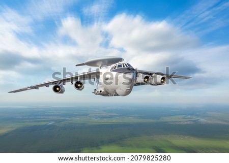 Heavy military transport aircraft with a locating and suppression device on the fuselage flies over the ground Royalty-Free Stock Photo #2079825280