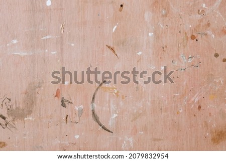 Colorful paint splashes on wooden board. Flat lay, top view. Abstract background from a painter workshop. White, brown and grey colors on brown plywood board. 