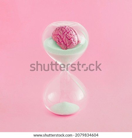 Conceptual, surreal, retro futuristic time clock scene with human brain in hourglass on isolated pastel pink background. Abstract medical creative concept of the transience of memory and brain fog. Royalty-Free Stock Photo #2079834604