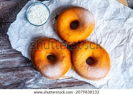 Delicious donuts with powdered sugar on wooden table