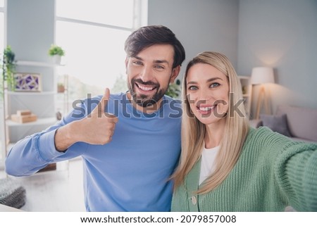 Self-portrait of two attractive cheerful people making web cam video call showing thumbup at home indoors
