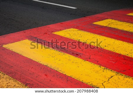 Pedestrian crossing road marking with yellow and red lines on asphalt