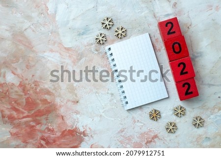 Red cubes with numbers and snowflake decorations spiral notebook as a new year and christmas concept placed on the left side on pastel colors background