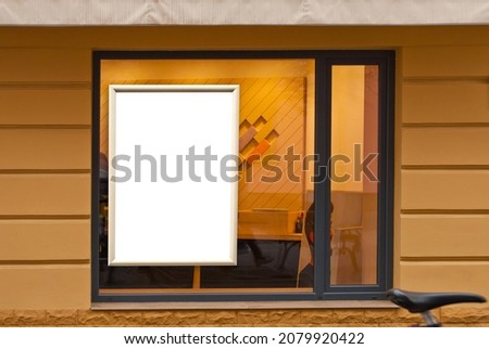Rectangular sign on the building. Copy space and space for text. Mockup for design. Blank template for advertising. White frame on a glass case. Advertising on the window of a restaurant or shop. Royalty-Free Stock Photo #2079920422