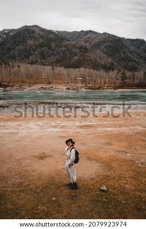 Female Traveler near river Looking at the Golden Autumn in Altai Mountains, Siberia, Russia.