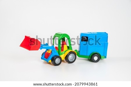 Children's toy plastic car isolated on white background. A multicolored excavator with a horse trailer.
