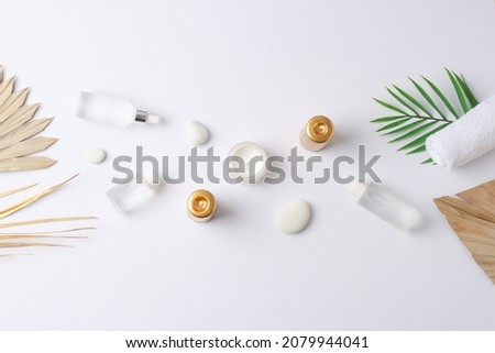 Spa treatment with cosmetic bottle, candles and palm leaf on white background. Flat lay, copy space