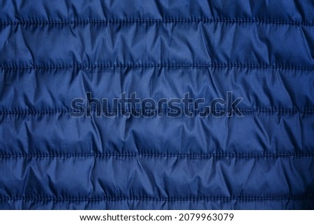 Blue texture of puffer, padded, down jacket. Background of urban winter outfit. Quilted pattern Royalty-Free Stock Photo #2079963079
