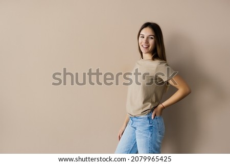 Portrait of a young woman posing isolated over beige background